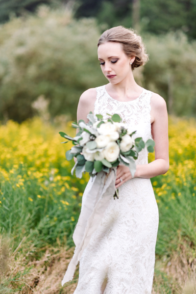 Bride to be holding a bouquet of flowers in an outdoor meadow wedding venue.